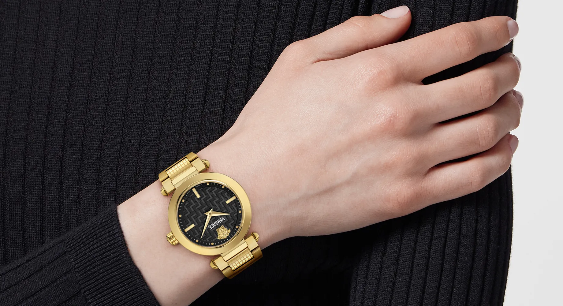 Gold and black women’s watch worn on a woman’s wrist.