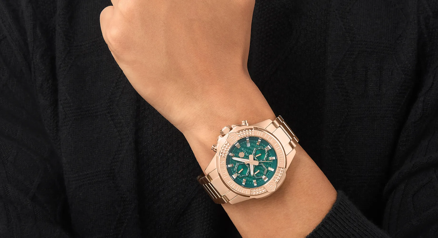 Green dial men’s watch worn on a man’s wrist.